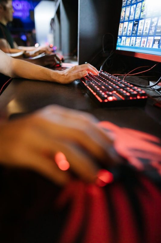 Gamers engrossed in a competitive PC gaming session with vibrant RGB peripherals.